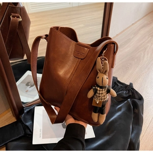 Close-up of vintage brown leather bucket bag featuring a cute rabbit charm and logo