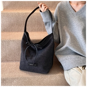 Detail of soft charcoal grey canvas tote bag with black leather bow and brand label