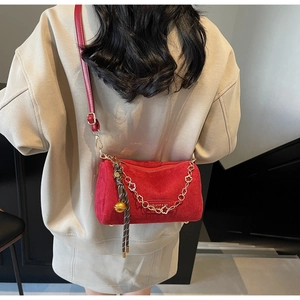 Dettaglio della borsa a tracolla rossa con catena floreale dorata indossata da modella