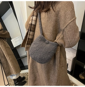 Close-up of a dark grey fuzzy wool bucket bag worn over a brown wool coat