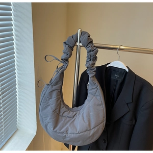 Detail of grey quilted crescent bag showing pleated strap and sleek nylon texture