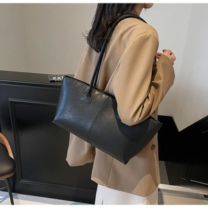 Chic black matte leather tote bag styled with a beige blazer for a minimalist office look