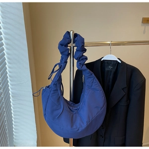 Detail of Klein blue quilted crescent bag with adjustable ruffled shoulder strap