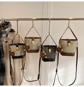 Detail of vintage canvas and leather bucket bag with metal lock and plush charm