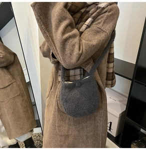 Mirror reflection showing a dark grey textured wool bucket bag with a brown autumn coat