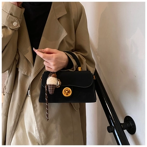 Detail einer schwarzen Lederhandtasche mit Goldring-Verschluss und Plüsch-Anhänger