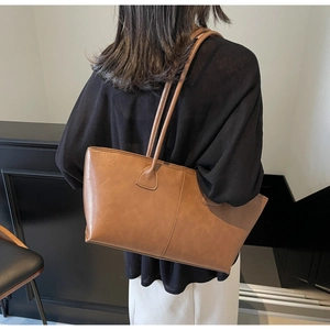 Brown leather tote bag featuring vertical stitching detail and long shoulder strap