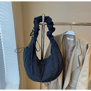 Detail of black quilted nylon half-moon bag featuring a unique gathered cloud shoulder strap