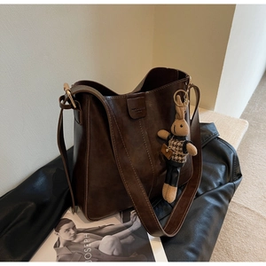 Detail of dark brown leather bucket bag with fashion engraving and cute rabbit charm