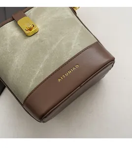 Detail of color-block bucket bag showing brown leather texture and golden metal lock
