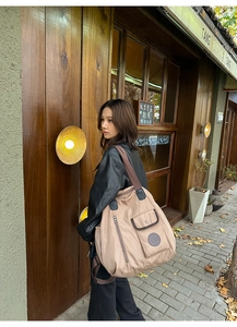 Detail of khaki nylon tote bag showing front snap pocket and durable shoulder strap