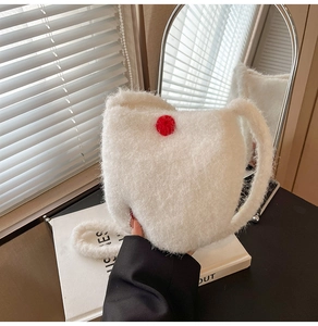 Close-up of fluffy white faux fur shoulder bag with a striking red plush ball charm