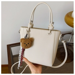 Close-up of cream lychee grain handbag with knotted handle and brown bear charm