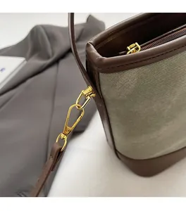 Detail of olive green canvas bag with brown leather trim and premium gold hardware hooks