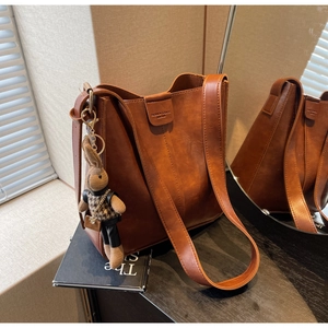 Detail of vintage brown leather bucket bag with plush rabbit charm and embossed logo