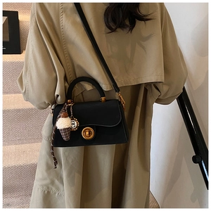 Detailaufnahme der schwarzen Umhängetasche aus Leder mit goldener Hardware und Anhängern