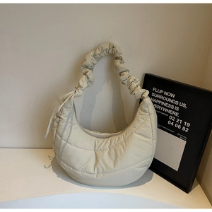 Detailed close-up of beige quilted moon bag featuring soft ruched handle and nylon texture