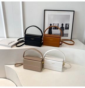 Detail view of box-shaped handbags in black brown beige and white on display stands