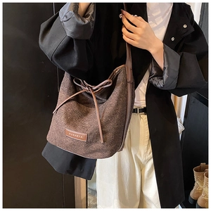 Detailed view of dark coffee wool bucket bag featuring leather drawstring bow and logo