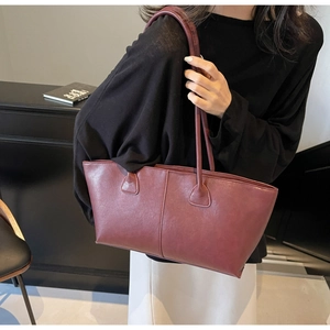 Detail of burgundy leather tote bag showing vintage texture and reinforced handle stitching
