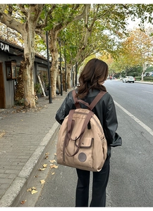 Detail of a large khaki nylon backpack with snap pockets and functional side compartments