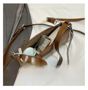 Vue de dessus du compartiment intérieur d'un sac bandoulière en cuir ciré marron avec chaîne