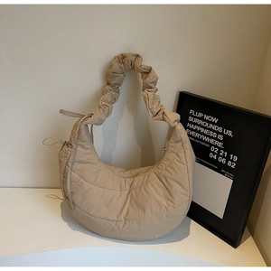 Detail of beige quilted nylon dumpling bag with elegant ruched strap and puffy texture