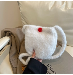 Close-up of white plush bucket bag with soft faux fur texture and a red pompom accent