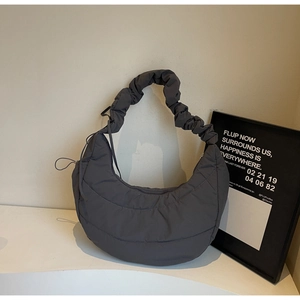 Detail of dark grey quilted crescent shoulder bag with puffy nylon and pleated strap