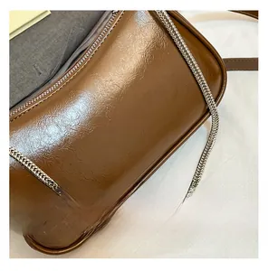 Détail macro du sac en cuir ciré marron avec une bandoulière en chaîne métallique