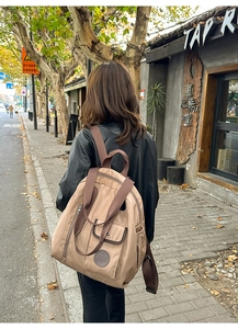 Close-up of a khaki nylon backpack featuring a flap pocket and round leather logo patch