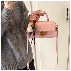 Detail der rosa Handtasche in Wildlederoptik mit goldenem Drehschloss und Anhänger