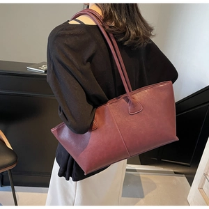 Side view of large burgundy tote bag worn over shoulder showing spacious trapezoid design