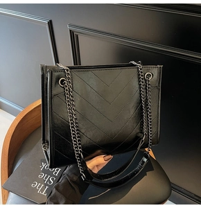 Close-up of black crossbody bag with chevron quilted pattern and dark metal chain strap