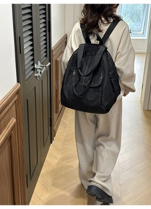 Detail showing the black multipurpose backpack with waterproof fabric on a model in a hall