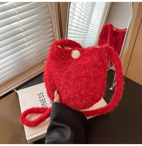 Macro detail of the red plush bucket bag showing soft texture and fuzzy ball decor