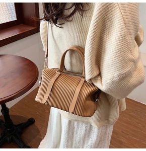 Detail der hellbraunen gefalteten Boston-Tasche mit verstellbarem Gurt am Modell