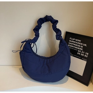 Detail of navy blue nylon crescent bag featuring quilted texture and ruffled strap