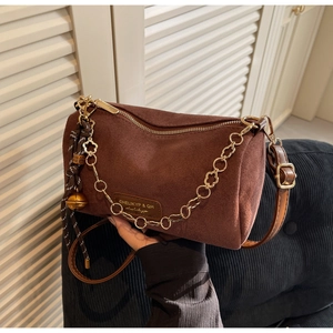 Dettaglio borsa a bauletto in camoscio marrone scuro con catena dorata e campanello