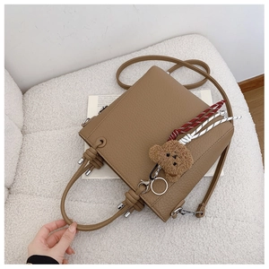 Khaki pebbled leather bucket bag with knotted handle and brown plush bear charm