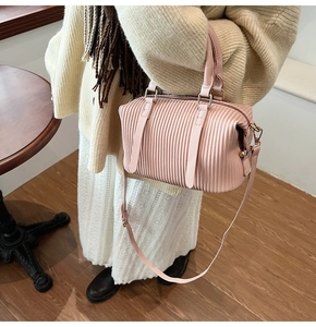 Detail der rosa Falten-Handtasche mit goldfarbenen Beschlägen und Schultergurt
