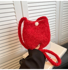 Detail view of red plush bucket bag featuring soft faux fur and white pompom detail