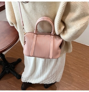 Detail der hellrosa Falten-Eimertasche mit vertikaler Textur und Leder-Handgriffen