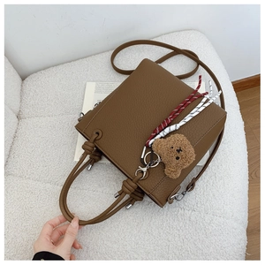 Close-up of caramel brown leather bucket bag with top handle and knot detail