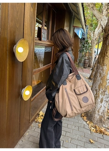 Detail view of khaki nylon travel bag featuring multiple zipper pockets and metal buckles