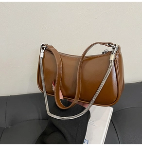 Détail du sac bandoulière vintage en cuir verni marron avec chaîne argentée et zip