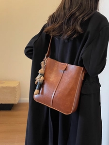 Retro brown large capacity bucket bag with rabbit pendant shown on a black wool coat