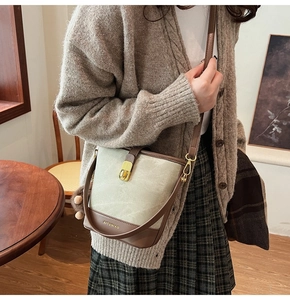 Close-up of beige contrast bucket bag with brown leather trim and golden twist lock