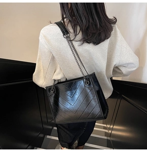 Grande borsa tote nera con trapuntatura a V e tracolla a catena indossata da modella