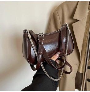 Nahaufnahme einer glänzenden dunkelbraunen Schultertasche mit schicker silberner Kette